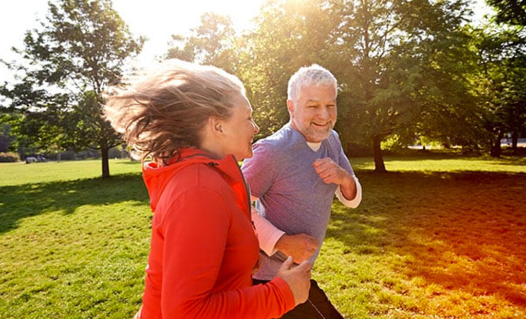 Ein älteres Paar joggt gelassen durch den Park bei Sonnenschein