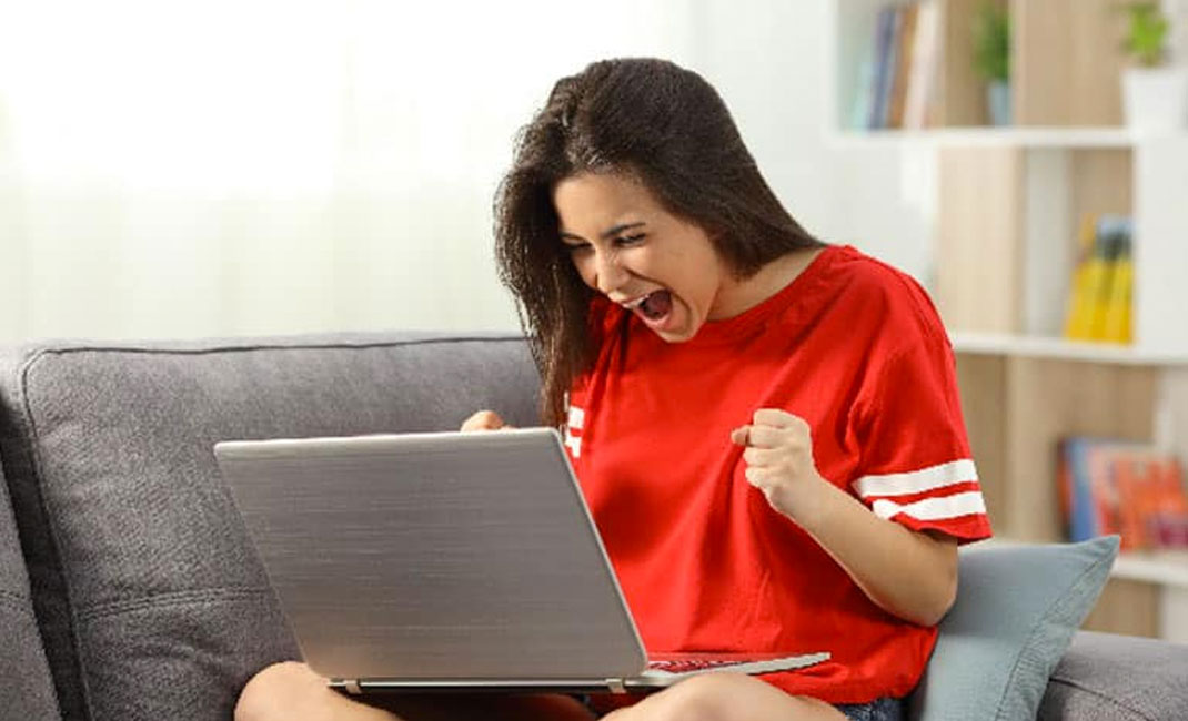 Schreiende Frau in rotem Shirt vor dem Laptop