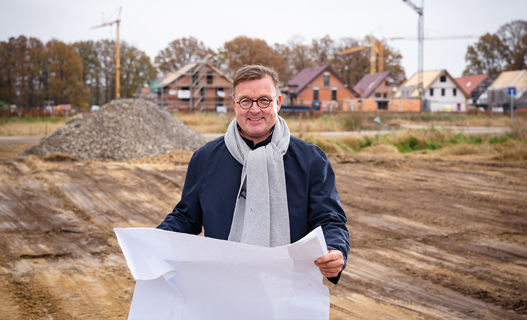 Ansgar Stahl mit einem Bauplan in einem Neubaugebiet